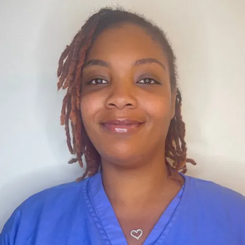 La Tonya Henry posing for the camera in scrubs behind a white backdrop