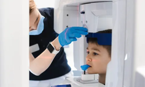 Unlicensed Dental Assistant with Radiology Certificate Taking X Ray of Young Patient