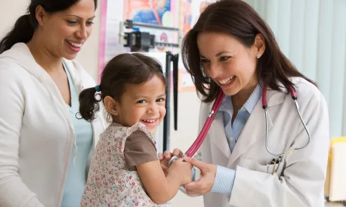 Pediatric Nurse Practitioner Smiling with Child Patient Taking Heart Rate