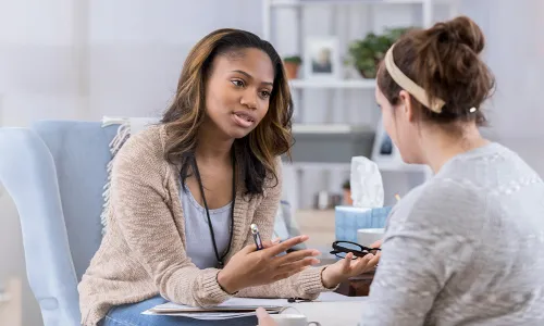 Substance Abuse Counselor with Psychology Degree Smiling with Client