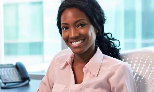 Medical Office Administrator Smiling at Desk