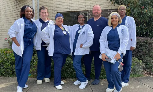 Accelerated BSN students in New Orleans smiling for photo outside wearing blue scrubs