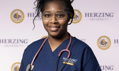 Herzing nursing student in blue scrubs wearing stethoscope smiling for portrait photo