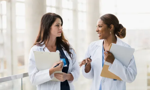 Advanced practice nurse with Doctor of Nursing Practice smiling with colleague