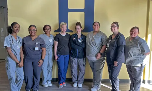 Group of Herzing Birmingham nursing students in scrubs smiling for photograph during simulation on campus