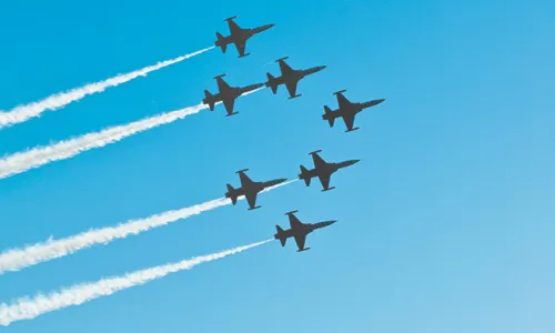 Jets flying in formation with a cloudless blue sky.