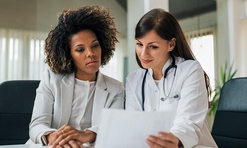 Healthcare Administrator with Physician Pathway Card Nurse administrator reviewing patient data with physician