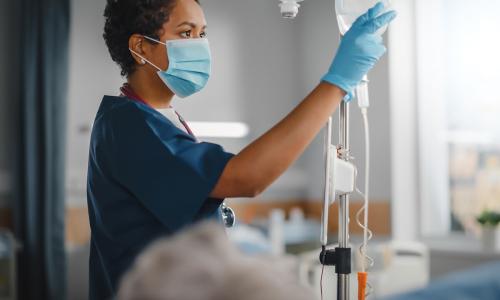 Registered Nurse in Mask Setting Up IV Registered nurse with associate degree wearing mask while setting up IV