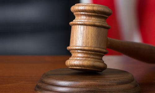 Gavel resting on bench with American flag in background 