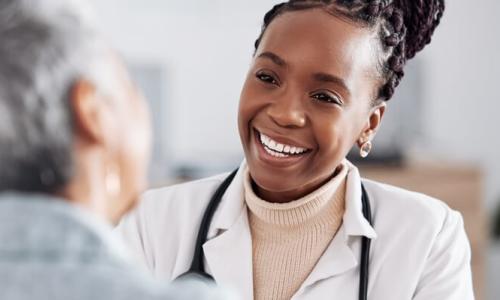 Women's health nurse practitioner smiling while speaking with female patient
