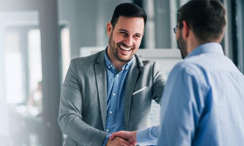 MBA graduate smiling and shaking hands after earning leadership position 