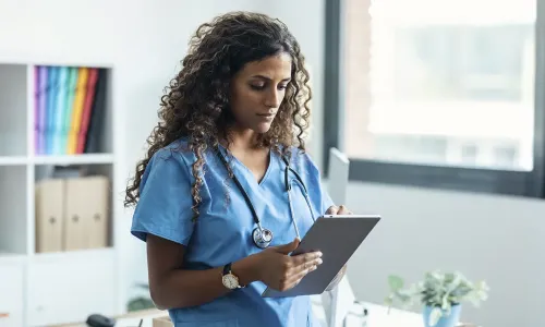 Nurse informaticist reviewing patient charts on handheld tablet