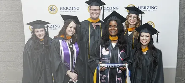 A group of Herzing University graduates celebrate their commencement, representing the success made possible through education and community support.