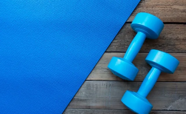 Dumbbells and yoga mat resting on floor of exercise room for PTA