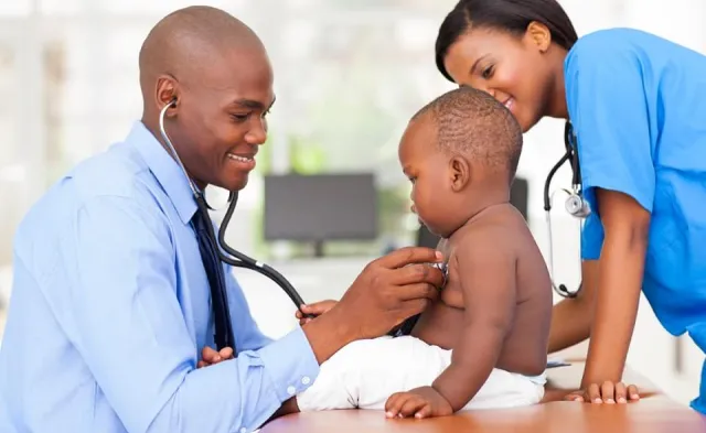 Family nurse practitioner working with nurse to take heart rate of pediatric patient