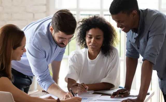 Three HR managers reviewing documents in team meeting