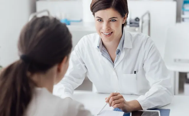 Adult-Gerontology Nurse Practitioner (AGNP) discussing treatment plan with patient and smiling