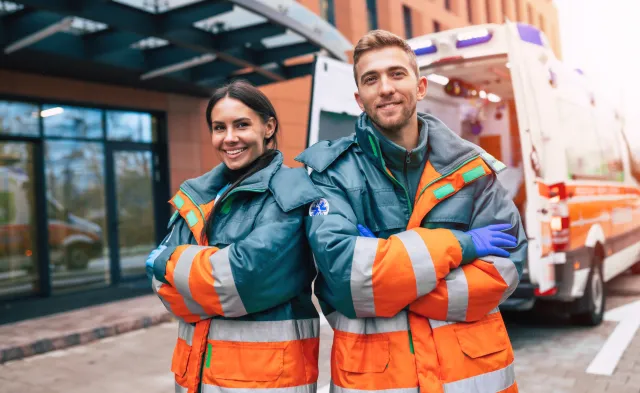 Emergency Medical Technicians Smiling Standing Besides Ambulance