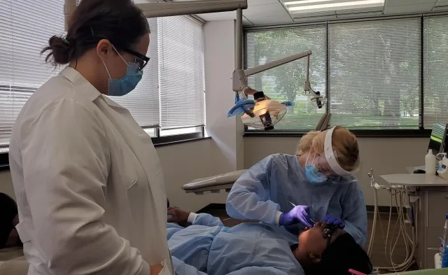 Dental Assistant in Dental Hygienist School Practicing Cleaning Patient Teeth