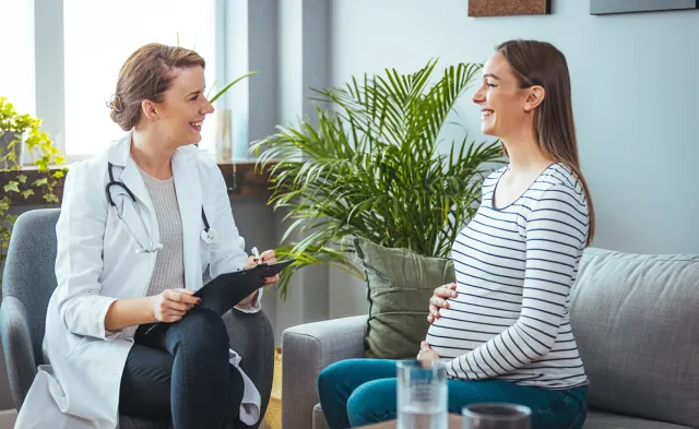 Women's health nurse practitioner smiling with pregnant patient