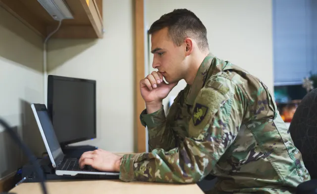 Shot of a young soldier using a laptop at a desk