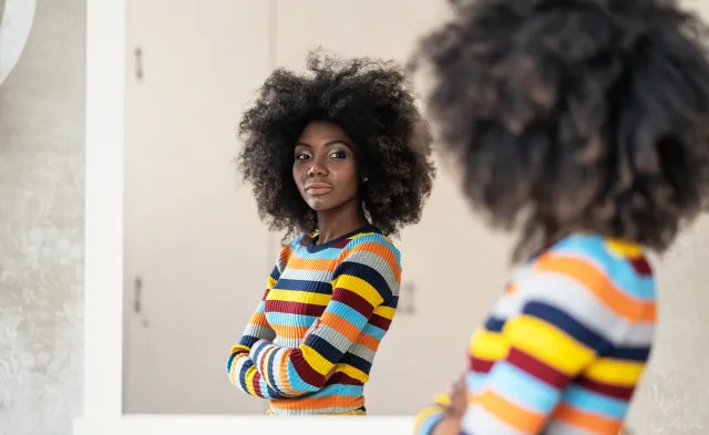 Woman with afro looking at her reflection in the mirror
