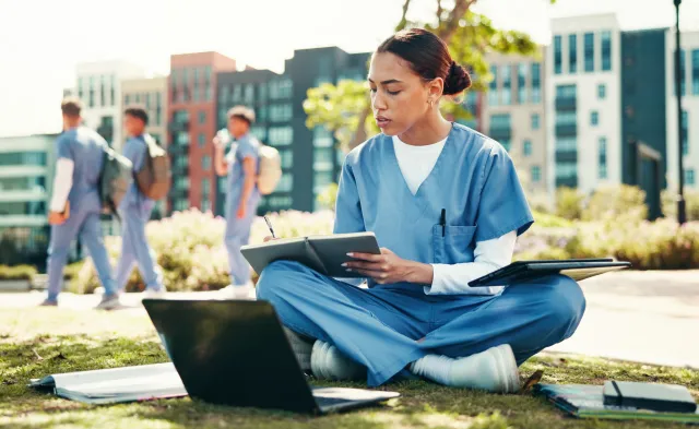 Woman, nurse or student writing with book for internship, studying or research at med school. Female person, healthcare candidate or intern taking notes with laptop for medical exam or test at campus