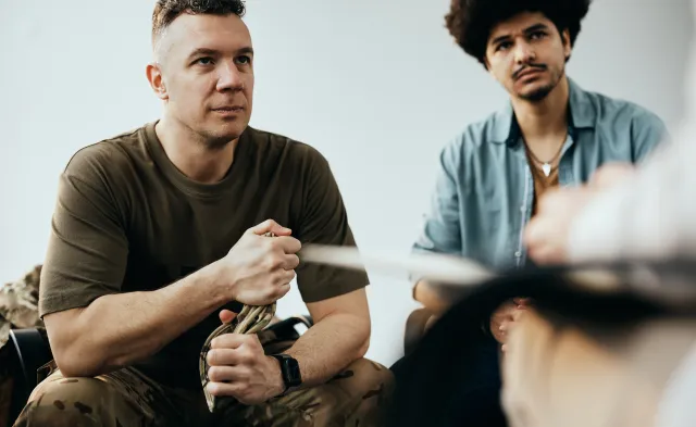 Military officer listening to therapist while having group therapy meeting at community center.
