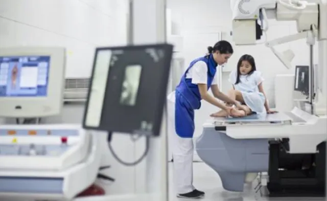 Radiologic technologist assisting a small child at an x-ray machine