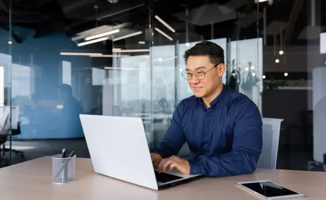 Smiling business professional seated at computer in bright conference room.