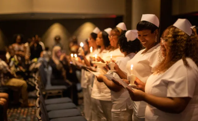 Herzing University Nurses standing with pinning lamps at the Herzing pinning ceremony