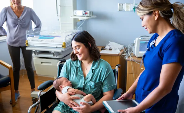 A young family consisting of a hispanic father and mother and their newborn baby boy in the hospital with grandparents, a nurse, and a pediatrician.