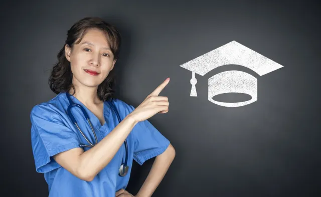 A nurse in blue scrubs points to a graduation cap symbol, representing nursing education, academic achievement, and career advancement.