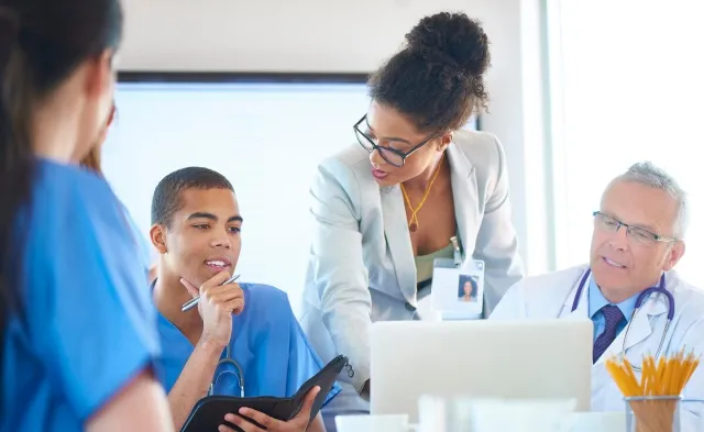 Nurse administrator speaking with other healthcare managers during team meeting