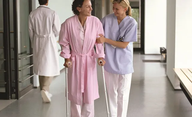 Occupational therapist helping patient walk on crutches