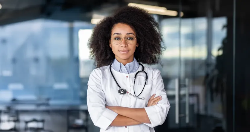 Nurse practitioner student smiling with arms crossed, wearing a white coat