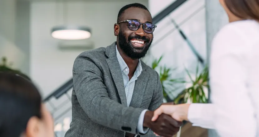 Interdisciplinary studies graduate shaking hands with business team and smiling in well lit conference room