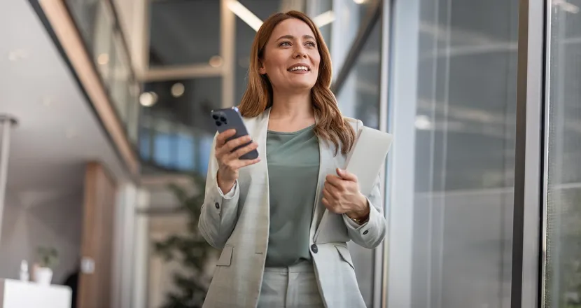 Herzing University online finance degree student using mobile devices in a professional setting, preparing for a fast-paced finance career