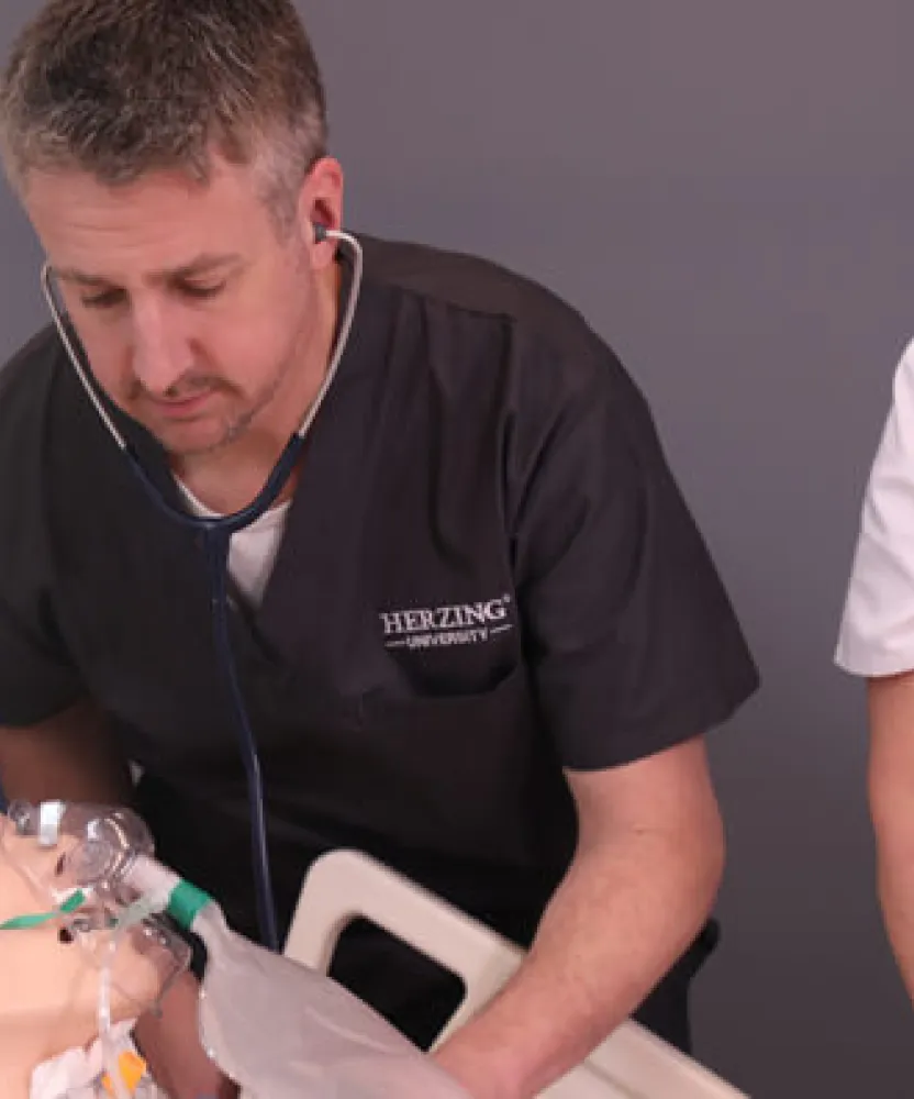 Male nursing student practicing on dummy in simulation labs under supervision of nursing instructor