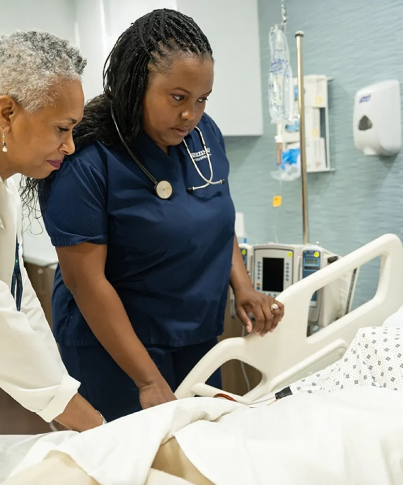Herzing University nursing instructor guides student during patient care simulation at the Atlanta campus.