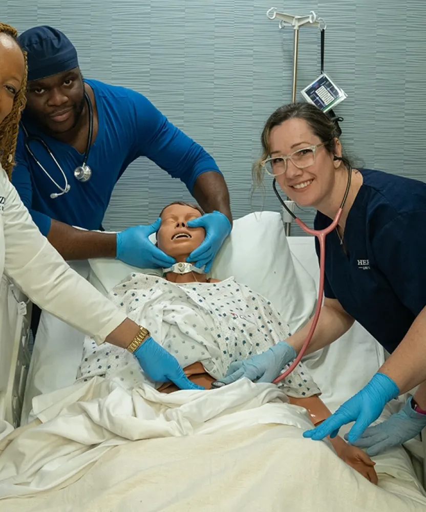 Herzing University Atlanta nursing students practice clinical skills on a training mannequin in the simulation lab.