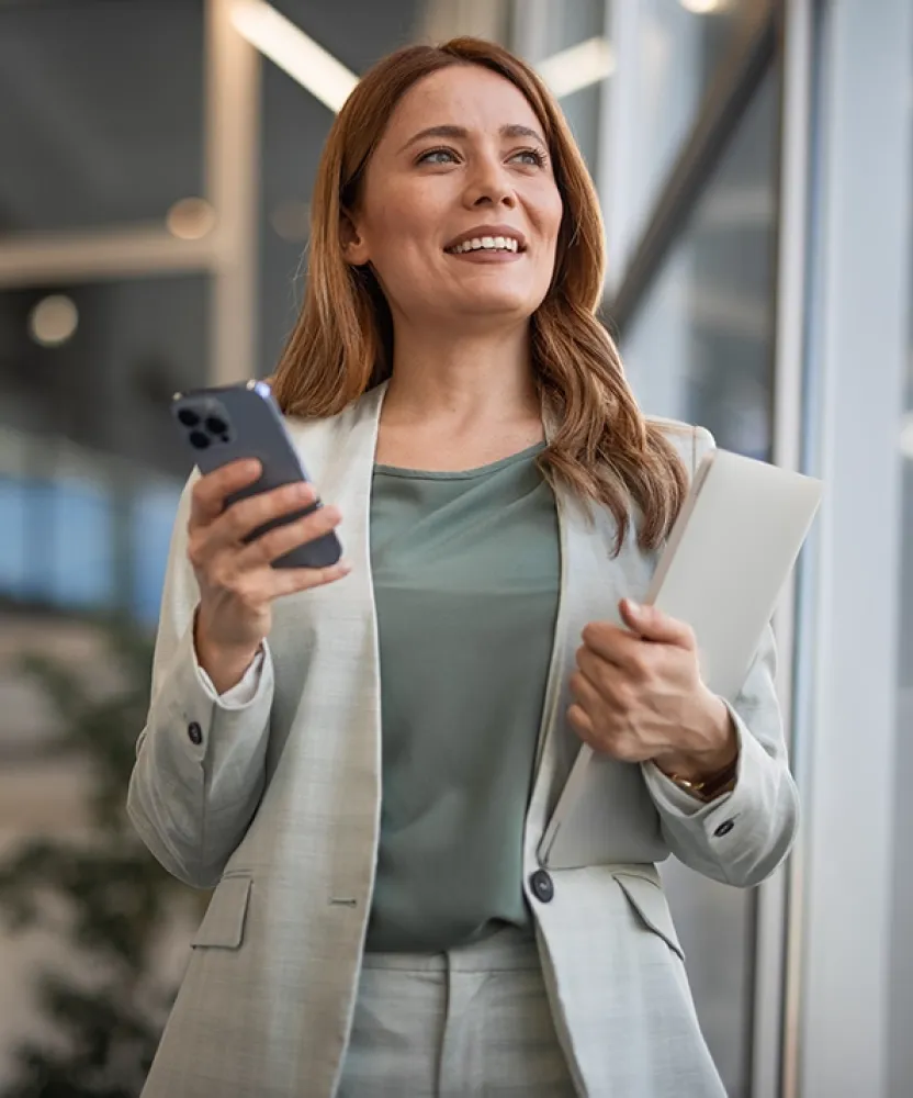 Herzing University online finance degree student using mobile devices in a professional setting, preparing for a fast-paced finance career