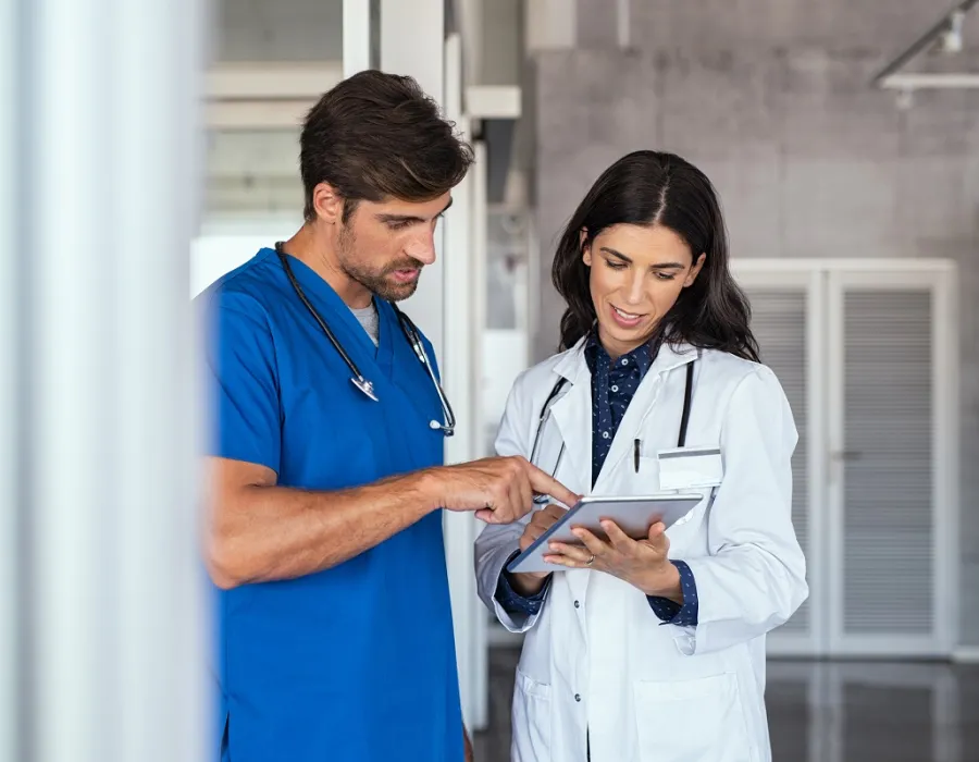 Nurse teacher reviewing patient charts with nursing student in blue scrubs