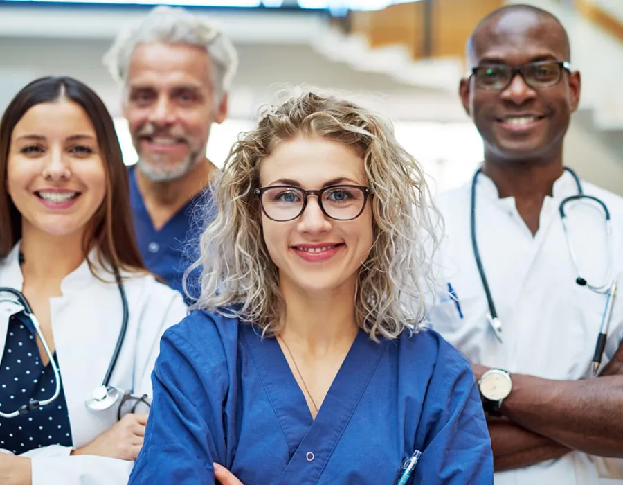 Group of four nurses posing in hospital smiling with arms crossed