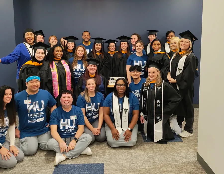 Group of Herzing University online nursing students posed for photo, some wearing a cap and gown after graduation