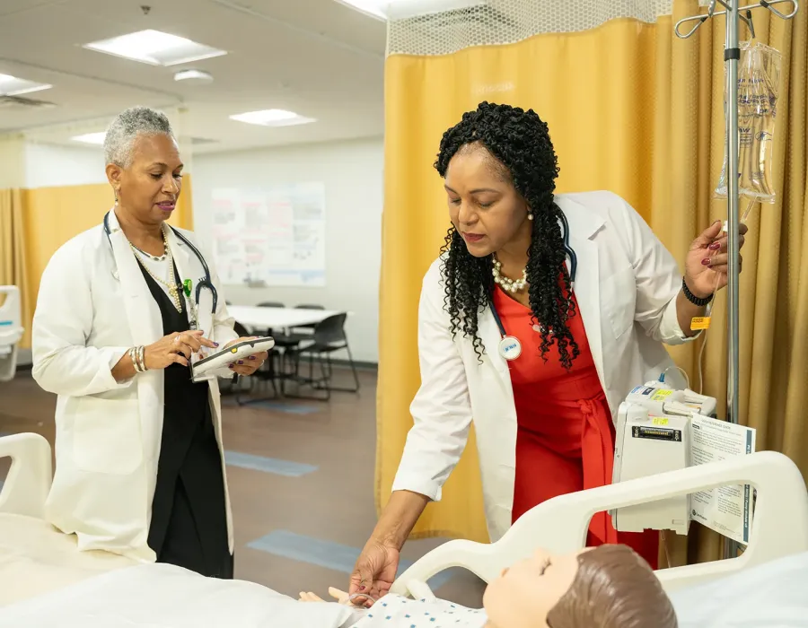 Nursing student in labs with instructor training on test mannequin