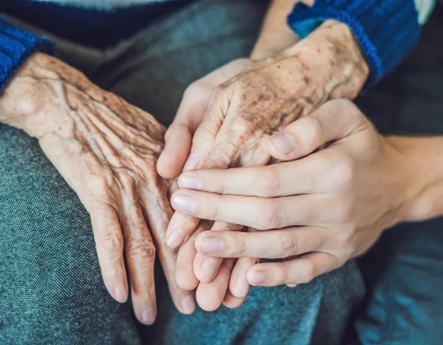 Two sets of hands: one elderly patient and a nurse providing assisted living services