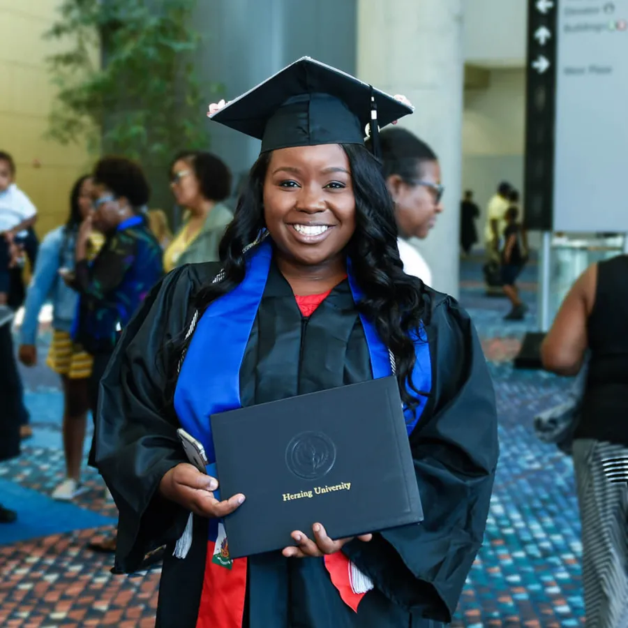 Herzing University Graduate Holding Diploma and Smiling