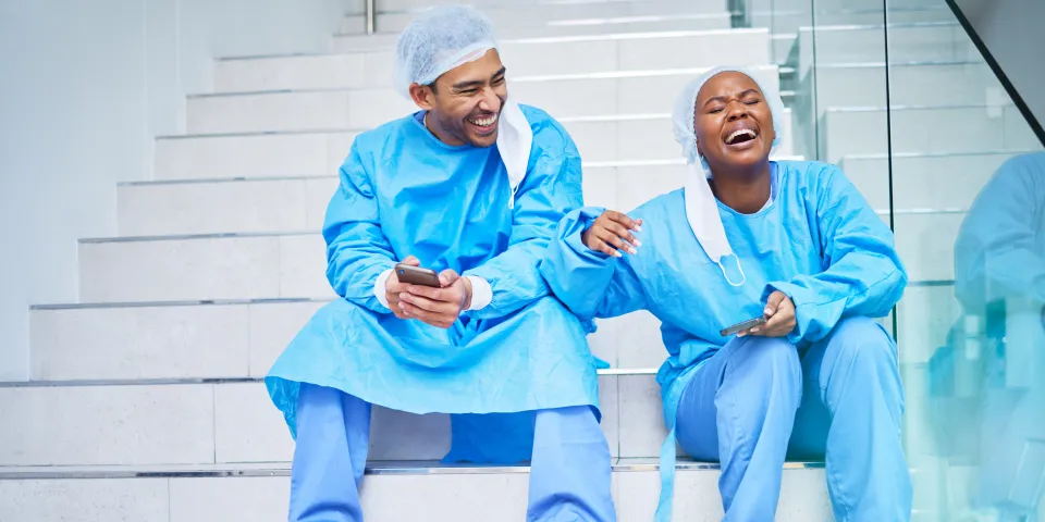 urgeon, conversation and laughing on hospital stairs with phone and funny meme. Healthcare, medical and doctor team relax with comic and conversation together with mobile and social networking