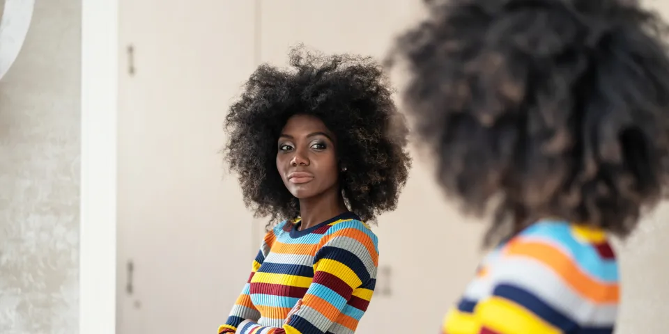 Woman with afro looking at her reflection in the mirror